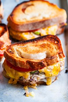 two grilled sandwiches sitting on top of a metal pan covered in cheese and tomato slices