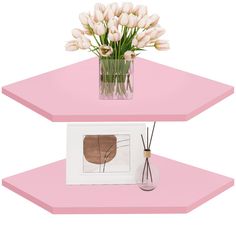 two pink shelves with flowers in vases on top and one shelf holding an art print