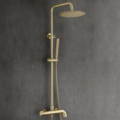 the shower head and handset are shown in this bathroom setting with grey walls, concrete flooring, and gold fixtures