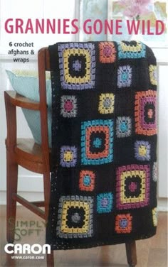 a crocheted granny blanket sitting on top of a wooden chair next to a wall