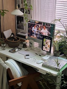 a desk with a computer monitor, keyboard and mouse next to a potted plant