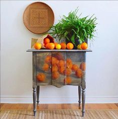 an old dresser with oranges and plants on top