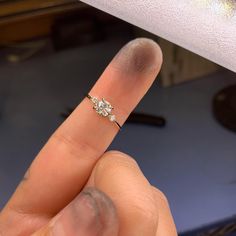 a person's finger with a diamond ring on it