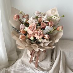 a bouquet of flowers sitting on top of a white cloth covered bed next to a window