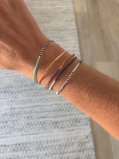 a woman's arm with three bracelets on it, one is multicolored