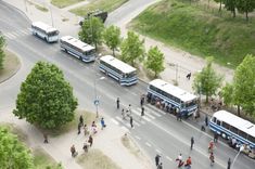 several buses are parked on the side of the road as people walk by and look at them