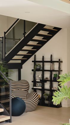 a living room filled with furniture and a stair case next to a wall mounted book shelf