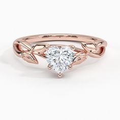 a rose gold ring with a heart shaped diamond in the center and leaves on each side