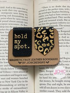 an open book with two magnets that say hold my spot and the words magnetic faux leather bookmark