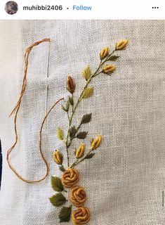 some yellow flowers and green leaves on a white cloth with orange thread in the middle