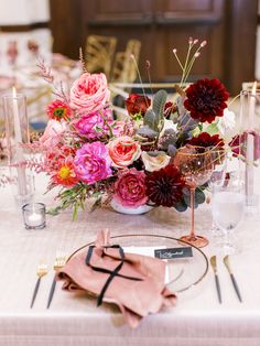 the table is set with pink and red flowers