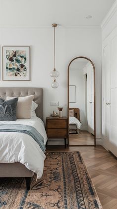 a bedroom with a bed, mirror and rug on the floor in front of it