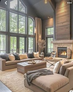 a living room filled with lots of furniture next to a fire place and large windows