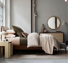 a bed sitting in a bedroom next to a window with lots of pillows on top of it