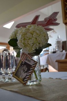 a vase filled with white flowers sitting on top of a table next to wine glasses