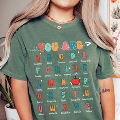 a girl with blonde hair wearing a green t - shirt that says you're abc and has an apple on it