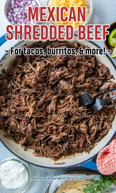 mexican shredded beef in a skillet with tortillas and sour cream on the side