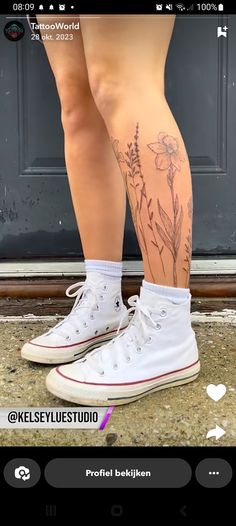 a person with tattoos on their legs standing in front of a door and wearing white sneakers