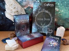 three books sitting on top of a table next to some rocks and crystals in front of a painting