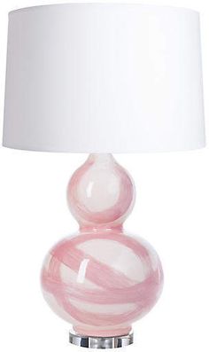 a pink and white lamp with a white shade on it's base is shown