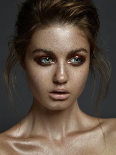 a woman with freckled skin and blue eyes is posing for a photo shoot