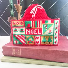 a cross stitch purse sitting on top of a book next to a pen and pencil holder