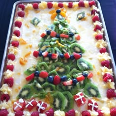 a christmas tree made out of fruit on top of a sheet cake covered in white frosting