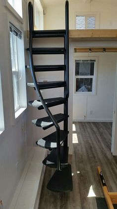 there is a spiral staircase in the middle of a room with wood flooring and white walls