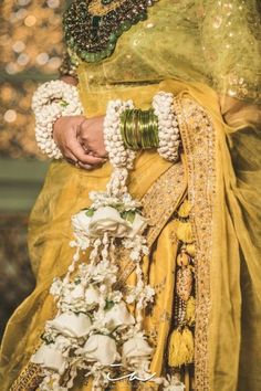 a woman in a yellow sari with white flowers on her chest and hands holding the neck