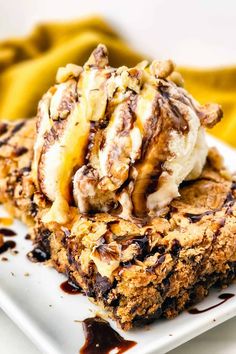 an ice cream sundae on a white plate with chocolate sauce and bananas in the background