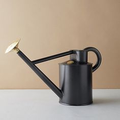 a black watering can with a gold tip