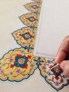 a hand is stitching an embroidered design on a piece of cloth with a needle