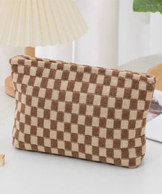 A cosmetic bag perfect for your skincare, make-up, hair care + more! Features a tan/mocha checker print and zip closure. Measurements: 10"W x 7.25"H Checkered Makeup Bag, Checkered Makeup, Essential Candles, Check Mate, Essential Pouch, Checker Print, Graphic Apparel, Beauty Sale, Makeup Pouch