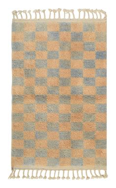 an orange and blue checkered rug with fringes on the bottom, in front of a white background