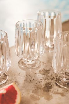 several glass cups sitting on top of a table next to a slice of grapefruit