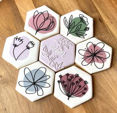 six decorated cookies with flowers on them sitting on top of a wooden table next to each other