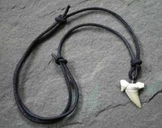 a black leather cord with a white bone pendant on it's end is laying on the ground