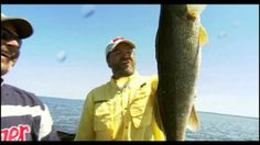 a man holding up a large fish while standing next to another man on a boat