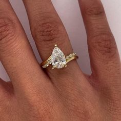 a woman's hand with a yellow gold ring and a pear shaped diamond on it