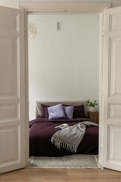 an open door leading to a bedroom with a bed and purple blankets on the bed