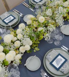 the table is set with blue and white plates, silverware, and floral centerpieces