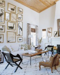 a living room filled with lots of furniture and pictures on the wall above it's fireplace