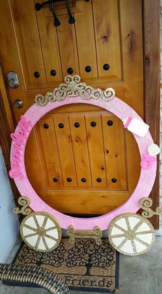 a pink and white wreath on top of a rug in front of a wooden door