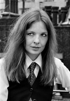 a woman with long hair wearing a vest and tie