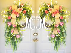 two wreaths with flowers and ribbons are on the front door of a house that is decorated for mother's day