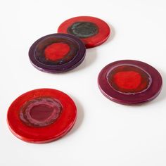 three red and one purple discs on a white surface