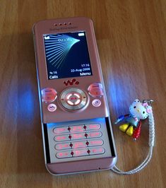 a pink cell phone sitting on top of a wooden table next to a small toy