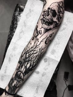 a man's arm with a skull and tree tattoo on it