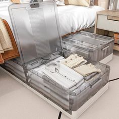 an open suitcase sitting on the floor in front of a bed with folded clothes inside