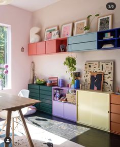 a room with many different colored drawers and shelves on the wall next to a table